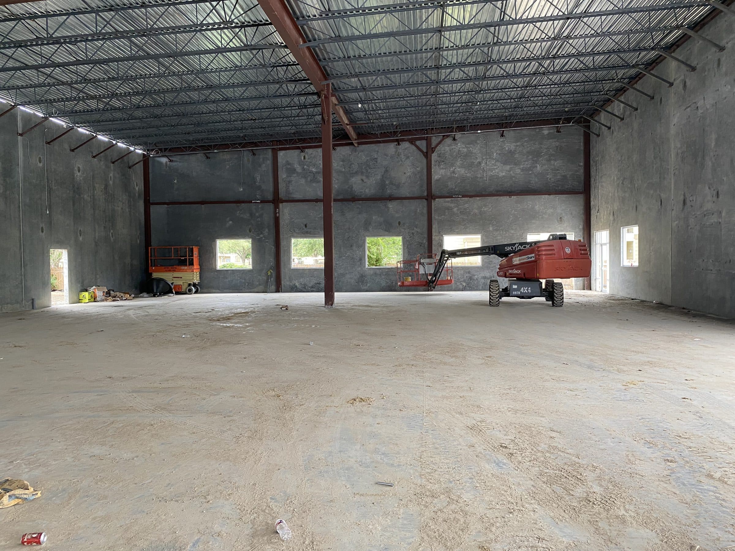 The open shell — clear-span volume under exposed steel joists before the build-out