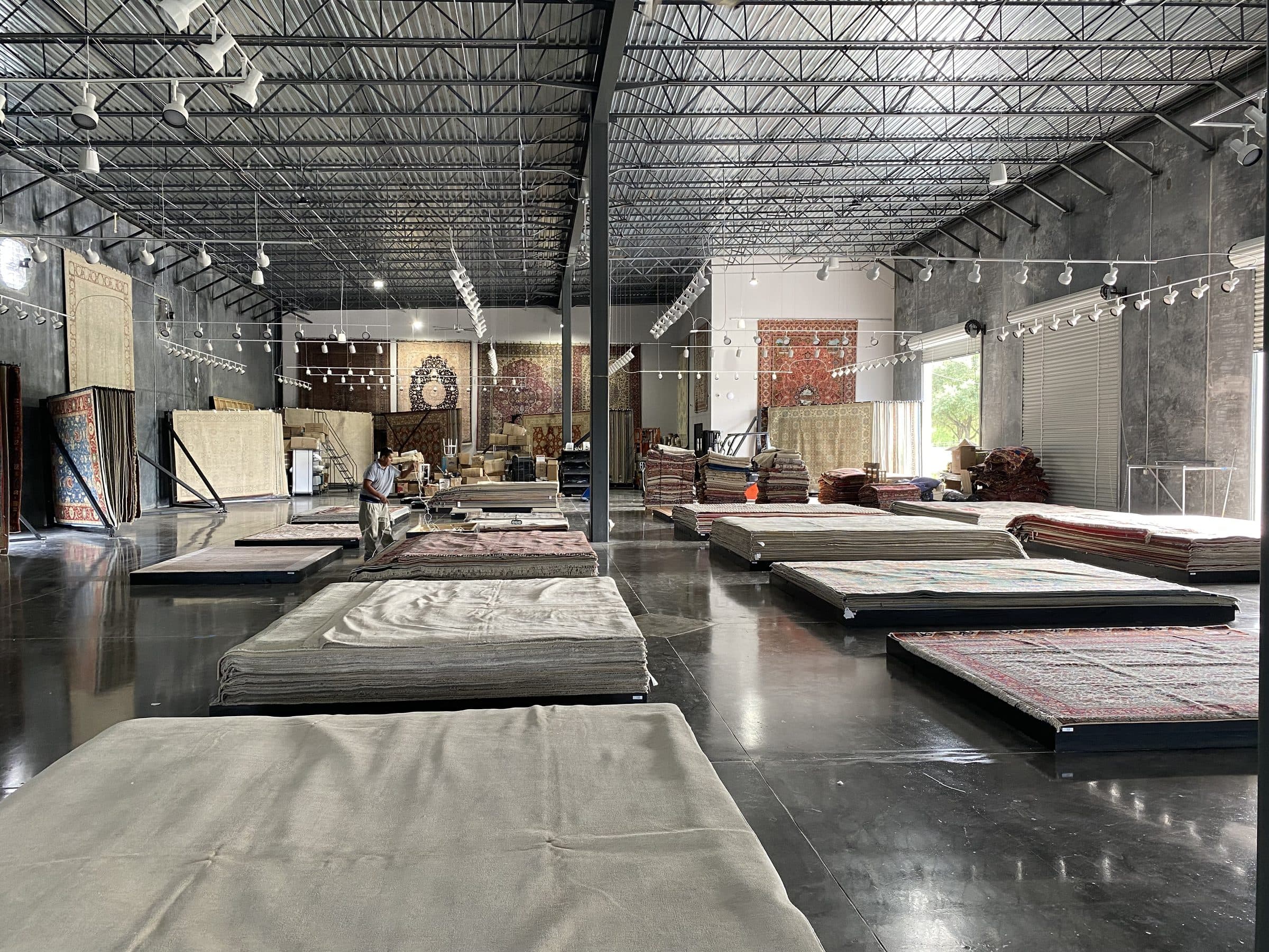13953 Fondren showroom — polished concrete floor, exposed steel roof structure, and track lighting over rug displays
