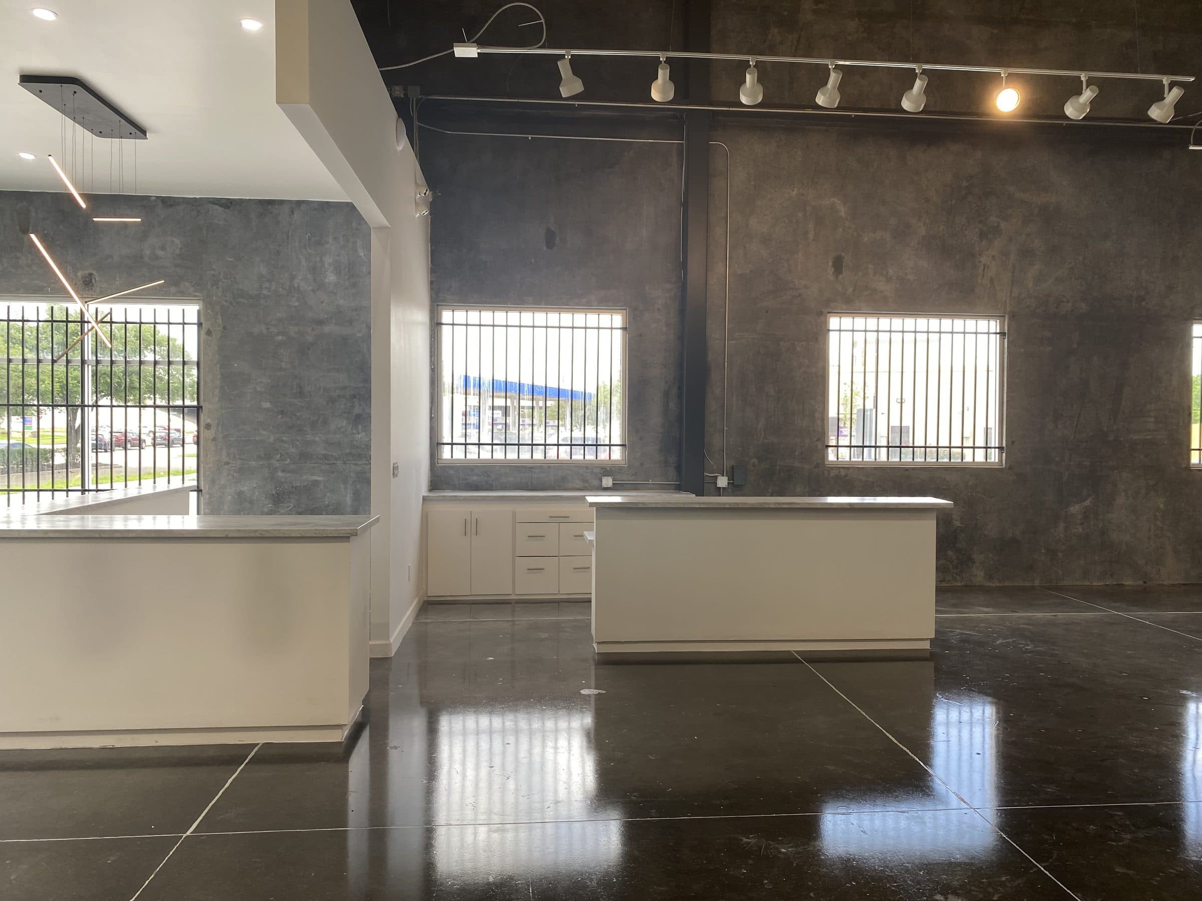 Service counter and millwork on polished concrete beneath linear pendants