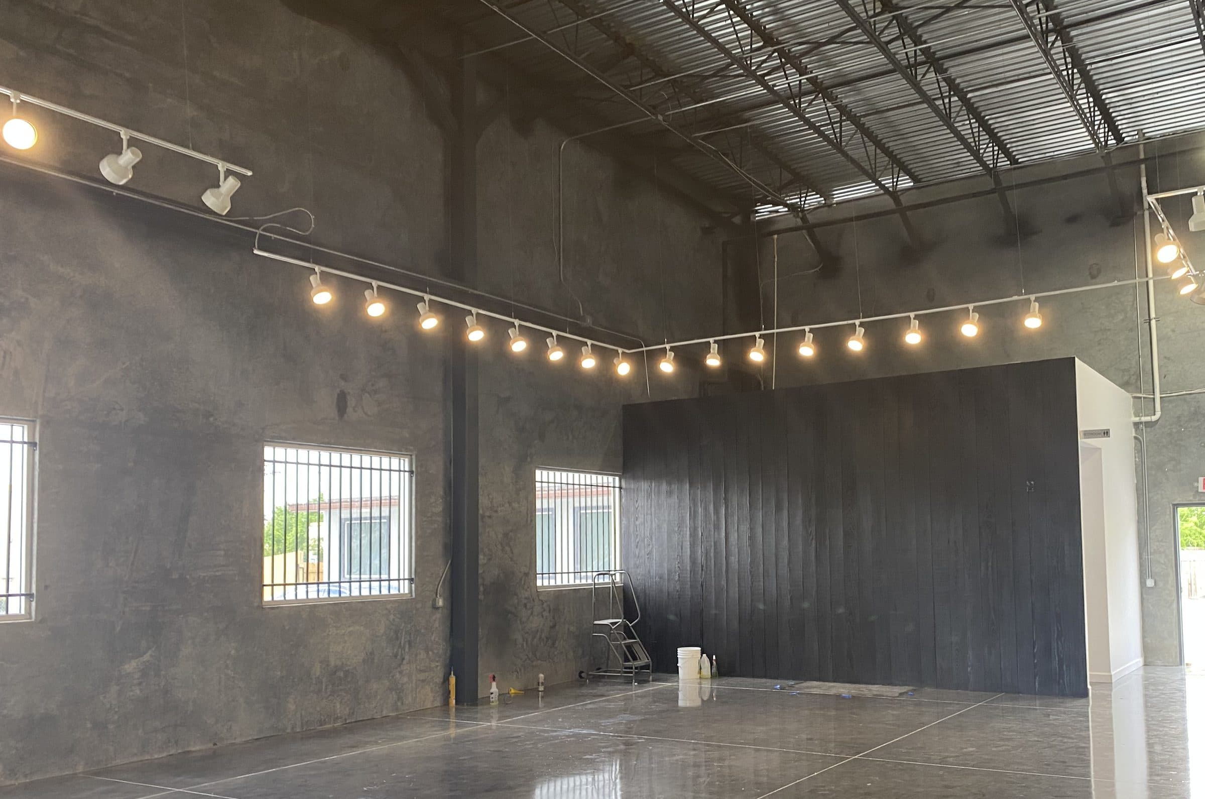 Track lighting tracing the perimeter of the showroom, reflected in the polished floor