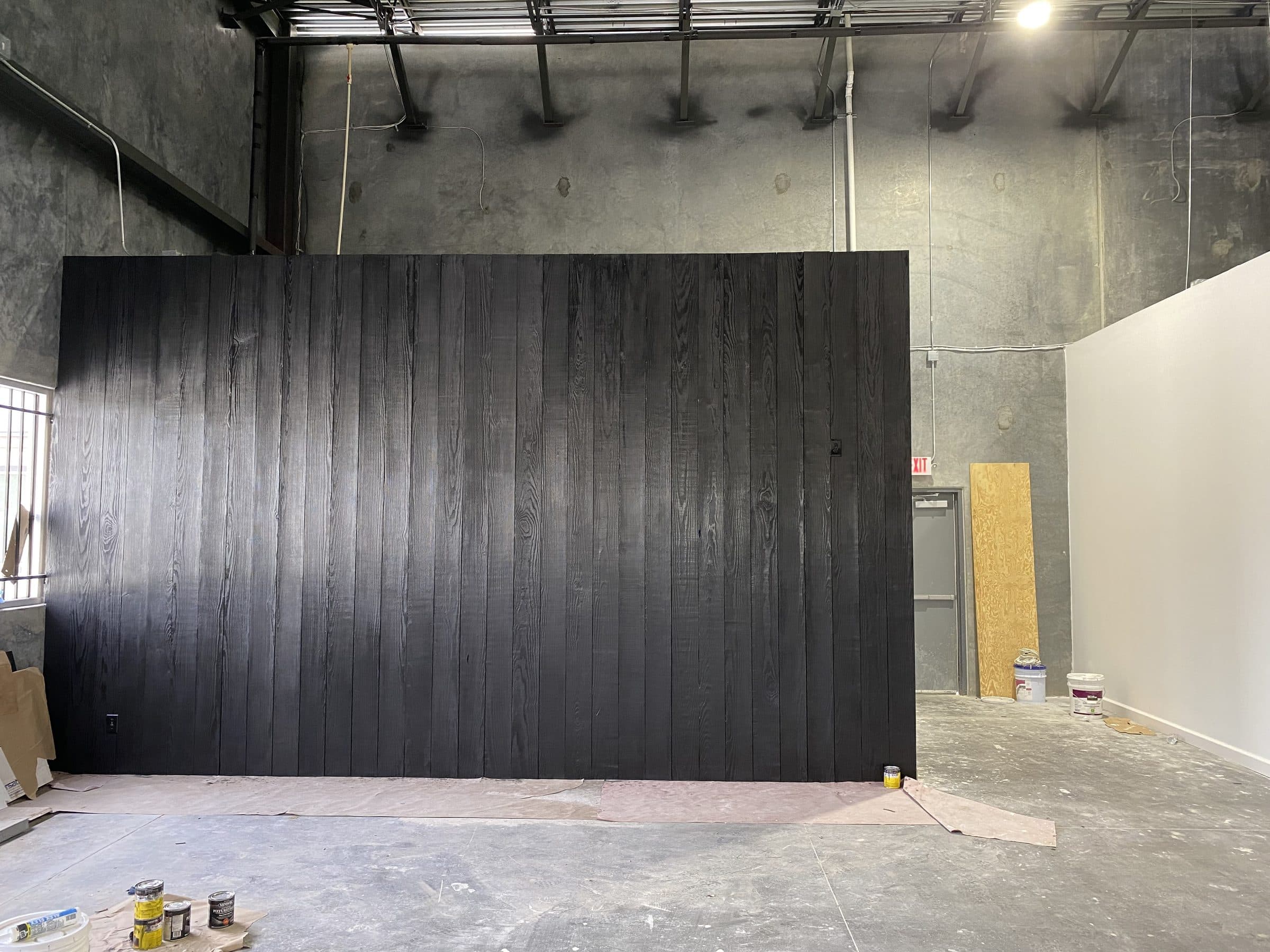 Blackened vertical-board timber feature wall against raw concrete