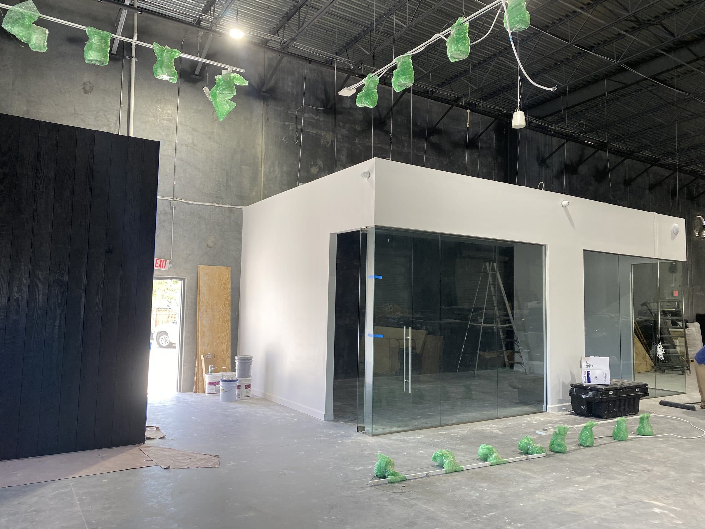 Interior build-out with glass-fronted offices and blackened timber wall under construction